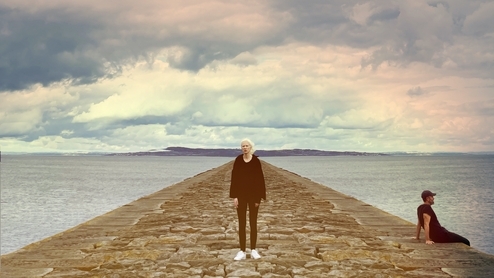 Photo of Lord Of The Isles and Ellen Renten standing on a pier in front of a rainbow sky