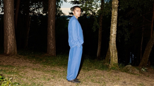 Kasra V poses in a forest while wearing a pale blue suit