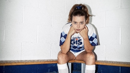 Photo of Giulia Tess sitting on a dressing room bench wearing a football kit