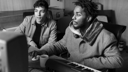 Photo of two young people making music in a studio