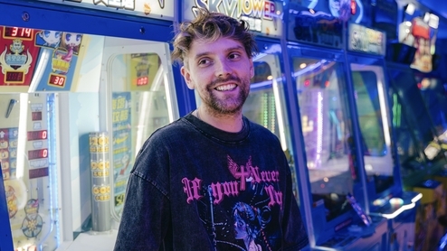 Photo of Faint Rings smiling and wearing a black tee in an arcade