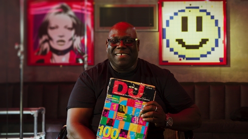 Carl Cox holding up the DJ Mag Top 100 DJs magazine from 1993