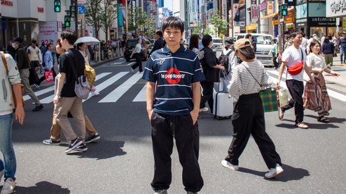Seimei stands in the middle of a Tokyo street wearing a navy football jersey