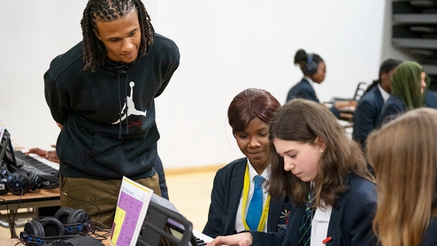 Photo of Nathan Aké helping school pupils learn the piano with his new music education initiative, 