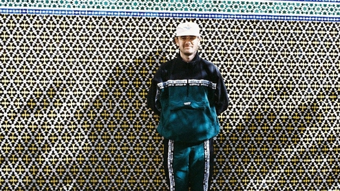 Photo of Gallegos wearing a navy and blue tracksuit against a tiled wall