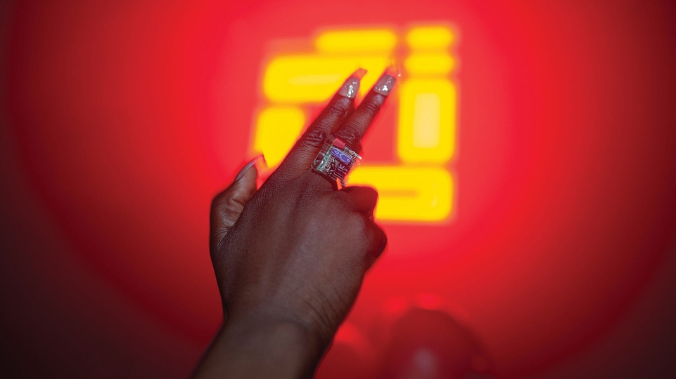 A gun finger held in front of a glowing Rupture logo on the dancefloor