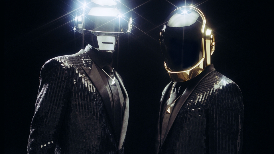Daft Punk wearing their iconic robot helmets and black suits 