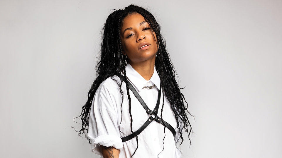 Press shot of KYRUH in a white shirt with the sleeves rolled up and a black harness