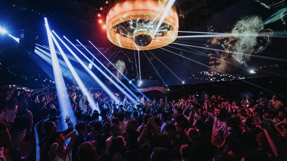 Photo of the crowd beneath a big orange chandelier at Club Chinois, Ibiza