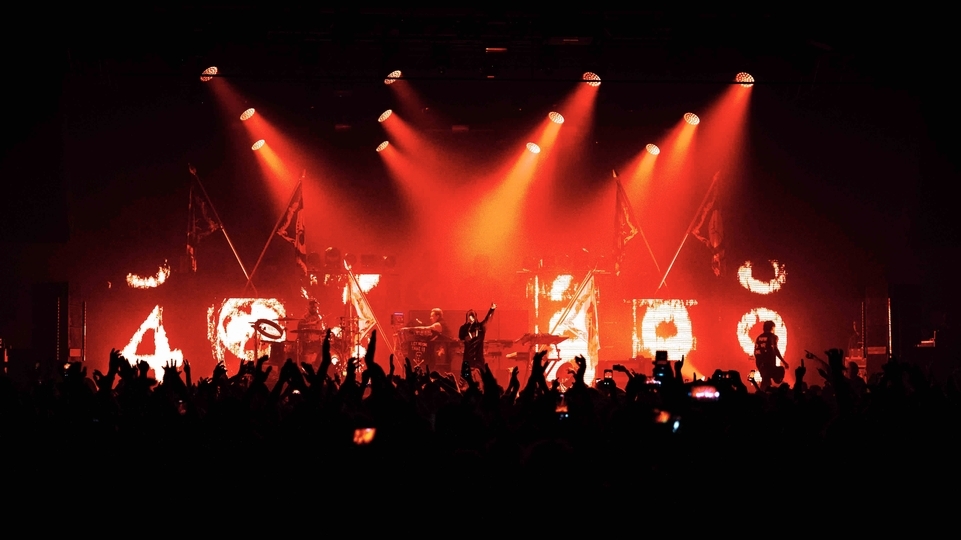 Photo of The Prodigy performing on stage with strobing red lights and a packed crowd
