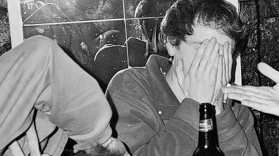 Black and white photo of Yokel sitting in a pub. His hands are covering his face.