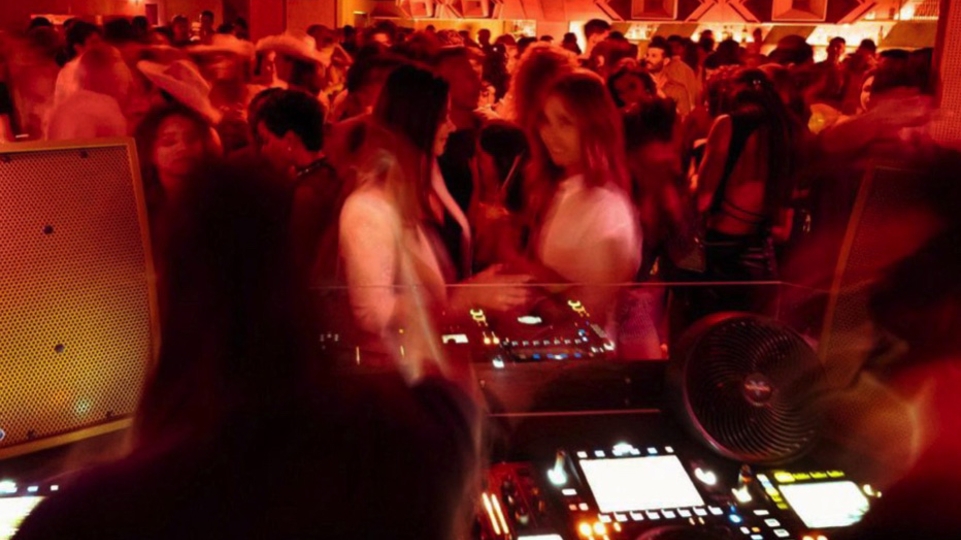 A crowd moves in a blur in front of the Dj decks at the new Miami venue, Jolene Sound Room