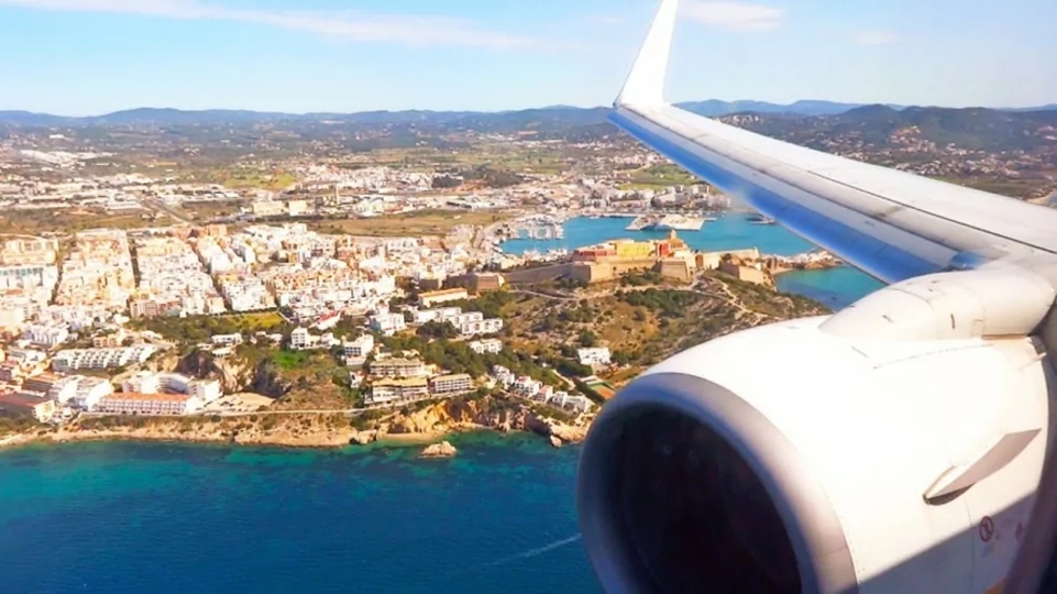 A photo of Ibiza taken from an airplane window with the wing in view