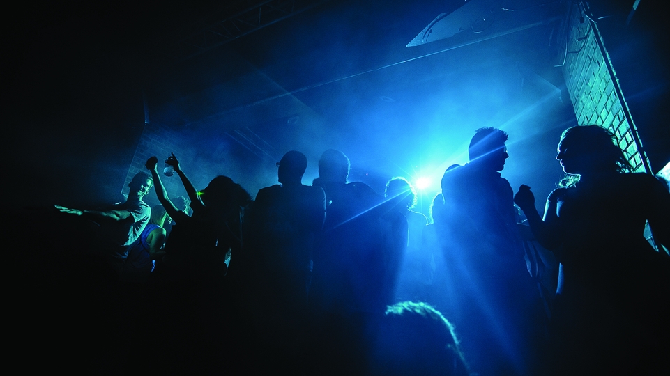Photo of people dancing in a blue-lit nightclub