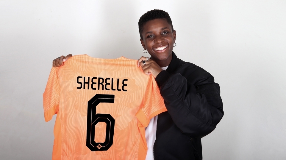 Photo of SHERELLE holding an orange football shirt reading ‘SHERELLE 6’