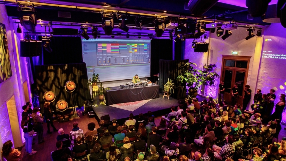 Photo of Reinier Zonneveld hosting a workshop in a large purple-lit room in front of a crowd of people