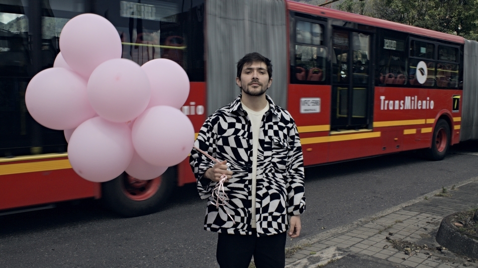 Photo of Lamediscos wearing a black and white abstract jacket and holding pink balloons