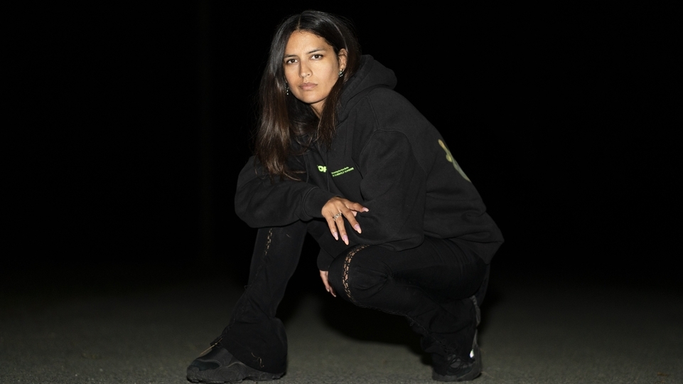 Photo of RONI wearing a black hoodie and trousers and crouching down
