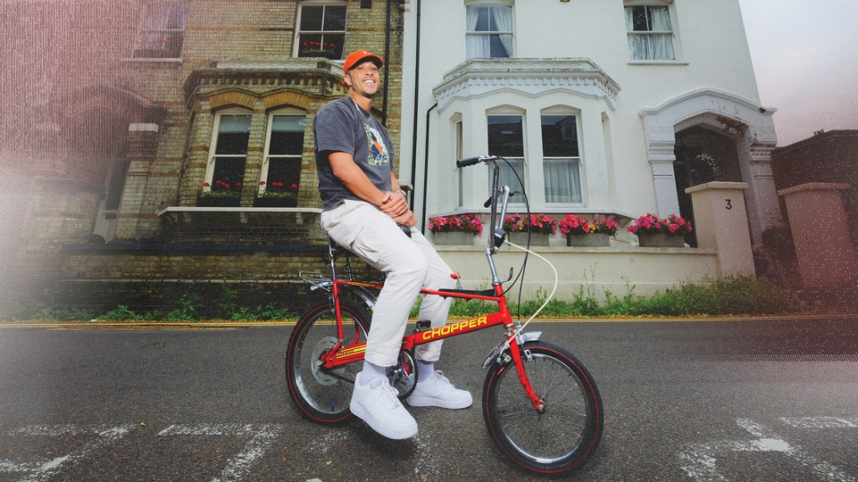 Photo of Melvo Baptiste on a red chopper bike on a street in Watford 