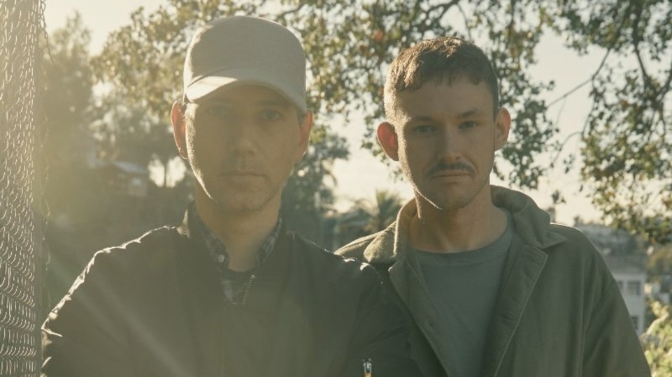 Hudson Mohawke & Tiga standing in front of trees