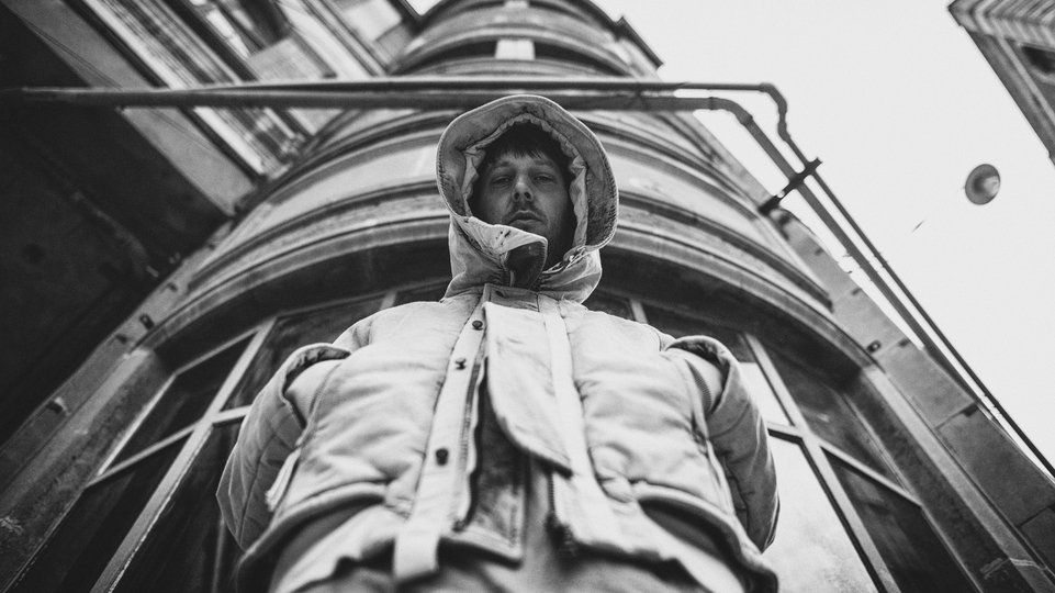 Black and white photo of DJ and producer R U OFF wearing a hooded coat 