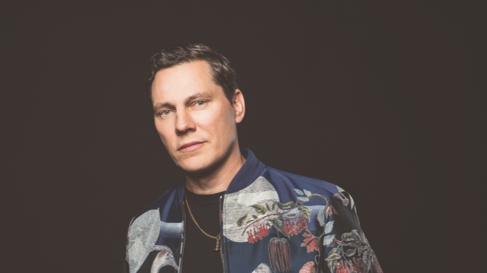 Tiesto poses in front of a black background