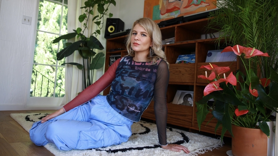 Photo of Masha Mar sitting on a rug next to a plant