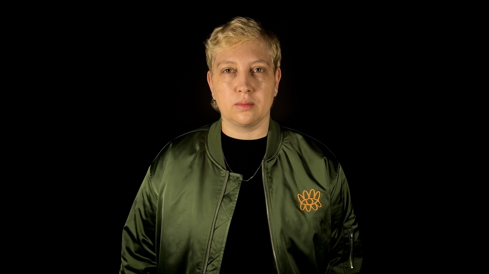 Photo of Alinka against a black background wearing a green army jacket