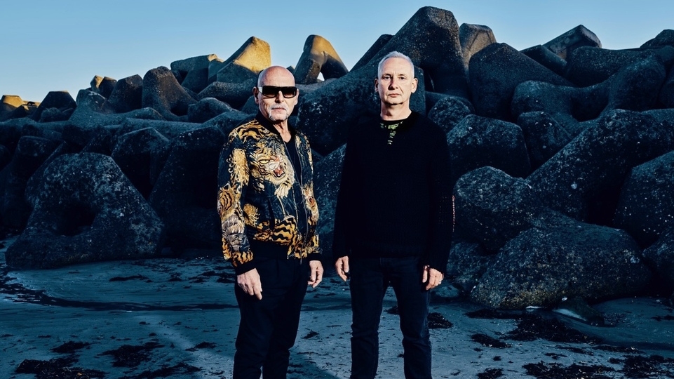 Photo of Orbital posing in front of large rock structure