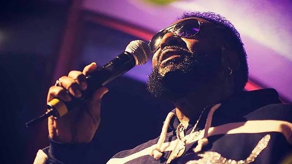 Chuck Roberts singing into a microphone while wearing shades