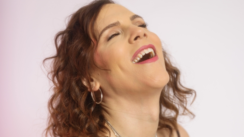 Photo of Eris Drew laughing against a pale pink background