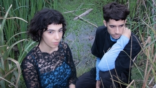 Photo of Lyas posing in dark outfits in front of a green marsh area